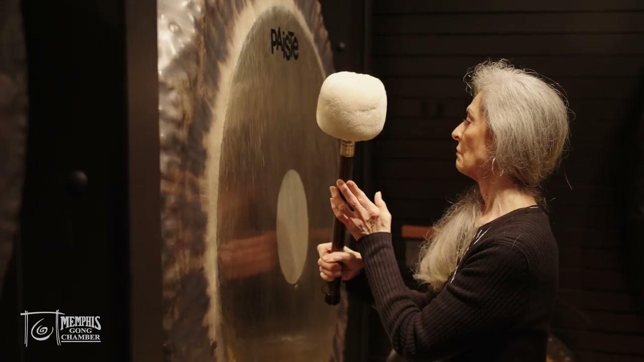 Sound healer playing a large gong